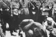 Austrian Nazis and local residents look on as Jews are forced to get on their hands and knees and scrub the pavement in March 1938