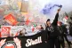 A demonstrator releases a smoke flare in front of a mural on