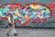 A man wearing a protective face mask walks past artwork in L