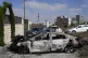 A Palestinian films a torched vehicle, seen the morning afte