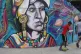 Boys play football in front of a mural of an indigenous Colo