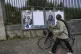 A woman pushes her bicycle as she looks at campaign posters 
