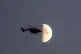 OLD WORLD ORDER: A police helicopter flies near the moon dur