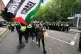 A protester with a Palestinian flag walks in front of police