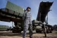 A Japanese soldier stands guard by a missile battery 