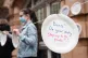 Protestors hang up paper plates carrying slogans calling for