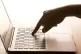 A woman's hand presses a key of a laptop keyboard