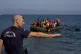 A Greek policeman gives instructions as migrants whose boat stalled at sea while crossing from Turkey to Greece approach the shore of the island of Lesbos, Greece, September 20, 2015