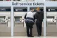 A member of staff assists a person at the ticket machines in Waterloo Station train station in London