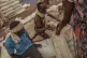 Porters pour sorghum grain into sacks at a food distribution in Gendrassa Refugee Camp, Maban, South Sudan, August 20, 2025