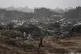 A Palestinian woman walks through a rainstorm past buildings destroyed in Israeli strikes in the Sheikh Radwan neighborhood of Gaza City, November 14, 2025