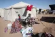 A Sudanese woman displaced from El-Fasher washes clothes outside her family's tent as children sit nearby at the newly established El-Afadh camp in Al Dabbah, in Sudan's Northern State, November 16, 2025