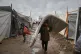 Salam Musa, 9, carries a mattress as he walks between tents after rainfall at a temporary camp in Deir al-Balah, in the central Gaza Strip, November 14, 2025