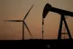 A pumpjack operates in the foreground while a wind turbine at the Buckeye Wind Energy wind farm rises in the distance, September 30, 2024, near Hays, Kansas, US
