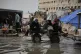 Palestinians ride in a cart pulled by a vehicle through a flooded street after stormy weather in Gaza City, December 10, 2025