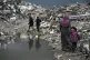 Palestinians walk through the rubble amid stormy weather in Gaza City, December 11, 2025