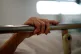 The hand of a patient grips the rail of a hospital bed