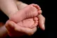 A mother holding the feet of her new born baby in her hand