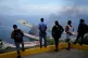Men watch smoke rising from a dock after explosions were heard at La Guaira port, Venezuela, January 3, 2026