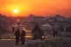 Palestinians walk through the ruins of destroyed buildings as the sun sets over Gaza City, January 4, 2026
