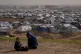 Palestinian children sit on an area near the tents of a makeshift camp for displaced people in Khan Younis, southern Gaza Strip, January 27, 2026