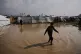 Displaced Palestinian children walk through a rain-soaked tent camp following heavy rainfall in Deir al-Balah, central Gaza Strip, February 24, 2026