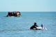People wade through the sea to board a small boat leaving the beach at Gravelines, France, in an attempt to reach the UK by crossing the English Channel, June 17, 2025