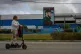 A woman rides an electric scooter past a factory displaying an image depicting the late Cuban leader Fidel Castro, bearing the words ‘Socialism or Death,’ in Havana, Cuba, March 19, 2026