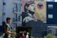 Pedestrians walk below an image of César Chavez on a mural in San Francisco, March 18, 2026