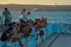People sit along the edge of an abandoned swimming pool across from a tanker terminal along the port of Matanzas, Cuba, March 30, 2026