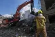 An excavator removes rubble as a firefighter sprays water on smoldering debris at the site of a strike that destroyed half of the Khorasaniha Synagogue and nearby residential buildings in Tehran, Iran, April 7, 2026