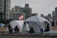Displaced people who fled Israeli strikes in southern Lebanon sit outside shelter tents in Beirut, Lebanon, April 24, 2026