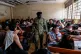 A Ugandan police officer walks past detainees seated in a room after authorities arrested dozens of foreigners in a crackdown on illegal migration, in Kampala, Uganda, April 28, 2026