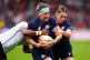 Scotland's Rachel Malcolm (centre) is tackled by Fiji's Manuqalo Komaitai (left) during the Women's Rugby World Cup 2025 Pool B match at Salford Community Stadium, August 30, 2025