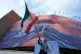 A man waves an Iranian flag for a pro-government campaign under a billboard with graphic showing Strait of Hormuz and sewn lips of US President Donald Trump in a square in downtown Tehran, Iran, May 6, 2026