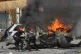 A person is seen inside a burning vehicle as men attempt to put out the fire after an Israeli air strike hits a car in the coastal town of Barja, south of Beirut, Lebanon, May 13, 2026