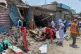 Plainclothes police officers, left, and local residents examine damage at the site of a bomb explosion at a market in Sarai Norag in Lakki Marwat, a district in Pakistan's Khyber Pakhtunkhwa province, May 12, 2026