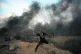 A Palestinian man prepares to throw a stone at Israeli soldi