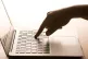 A woman's hand pressing a key of a laptop keyboard
