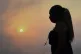 A woman wearing a mask walks wearing her cross at sunset dur