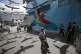The shadows of synthetic macaws are cast on the pavement bac