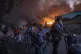 Refugees and migrants carrying their belongings flee a fire 