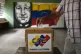 A man casts his ballot in front of a mural of late Venezuela