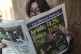 A woman reads a newspaper showing the results of the previou