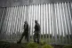 Police officers patrol alongside a steel wall at Evros river