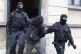 Police officers lead a suspect out of a building entrance du