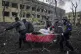 Ukrainian emergency employees and volunteers carry an injure