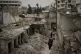 Women walk in a neighborhood heavily damaged by airstrikes i