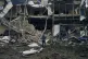 A woman stands in front of destroyed buildings after the Rus