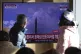 People watch a TV screen showing a news program about North 